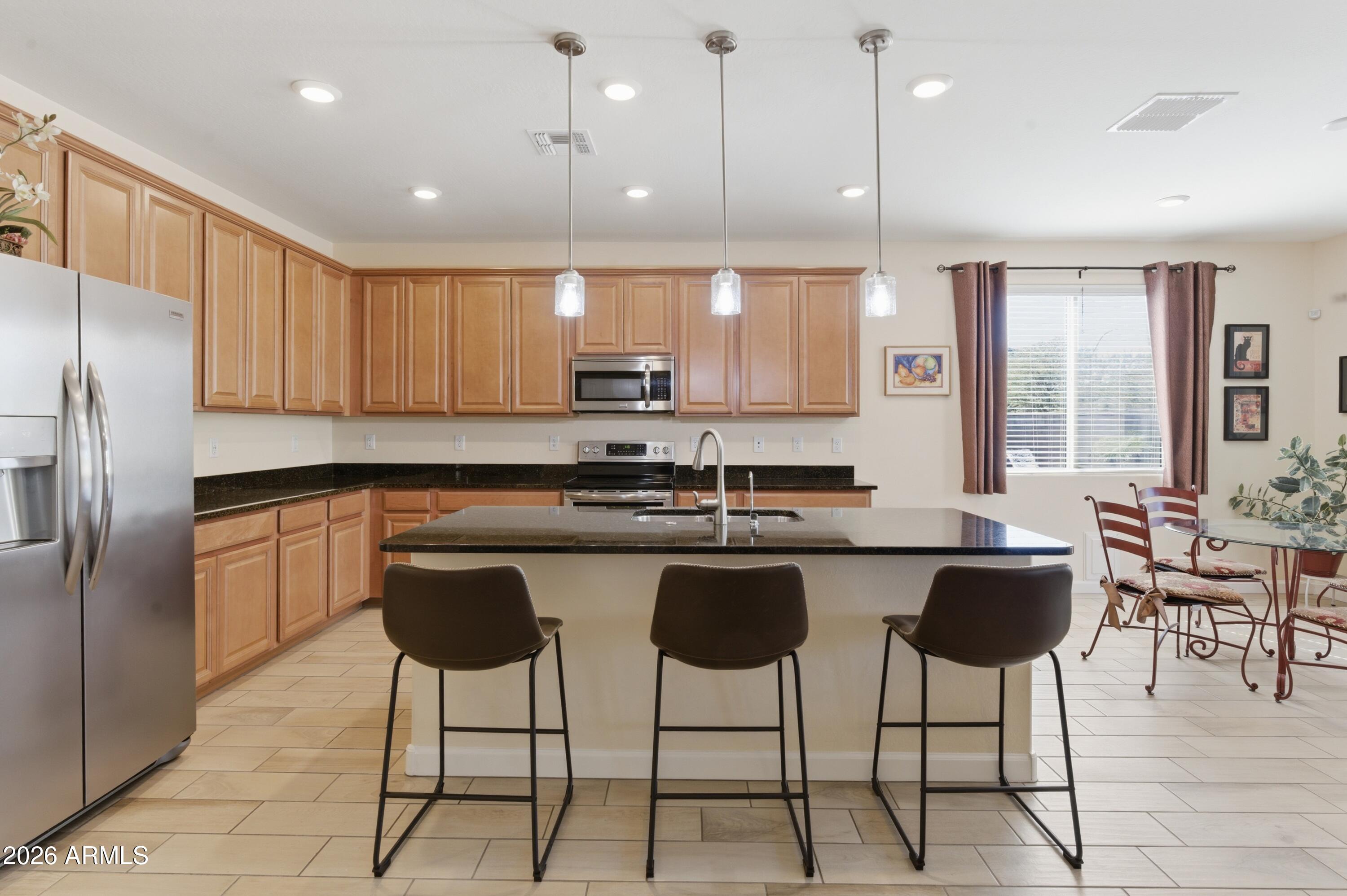 4654 North 204th Lane Buckeye, AZ 85396 - Photo 11 of 41 a kitchen with stainless steel appliances granite countertop a stove a sink a refrigerator and chairs