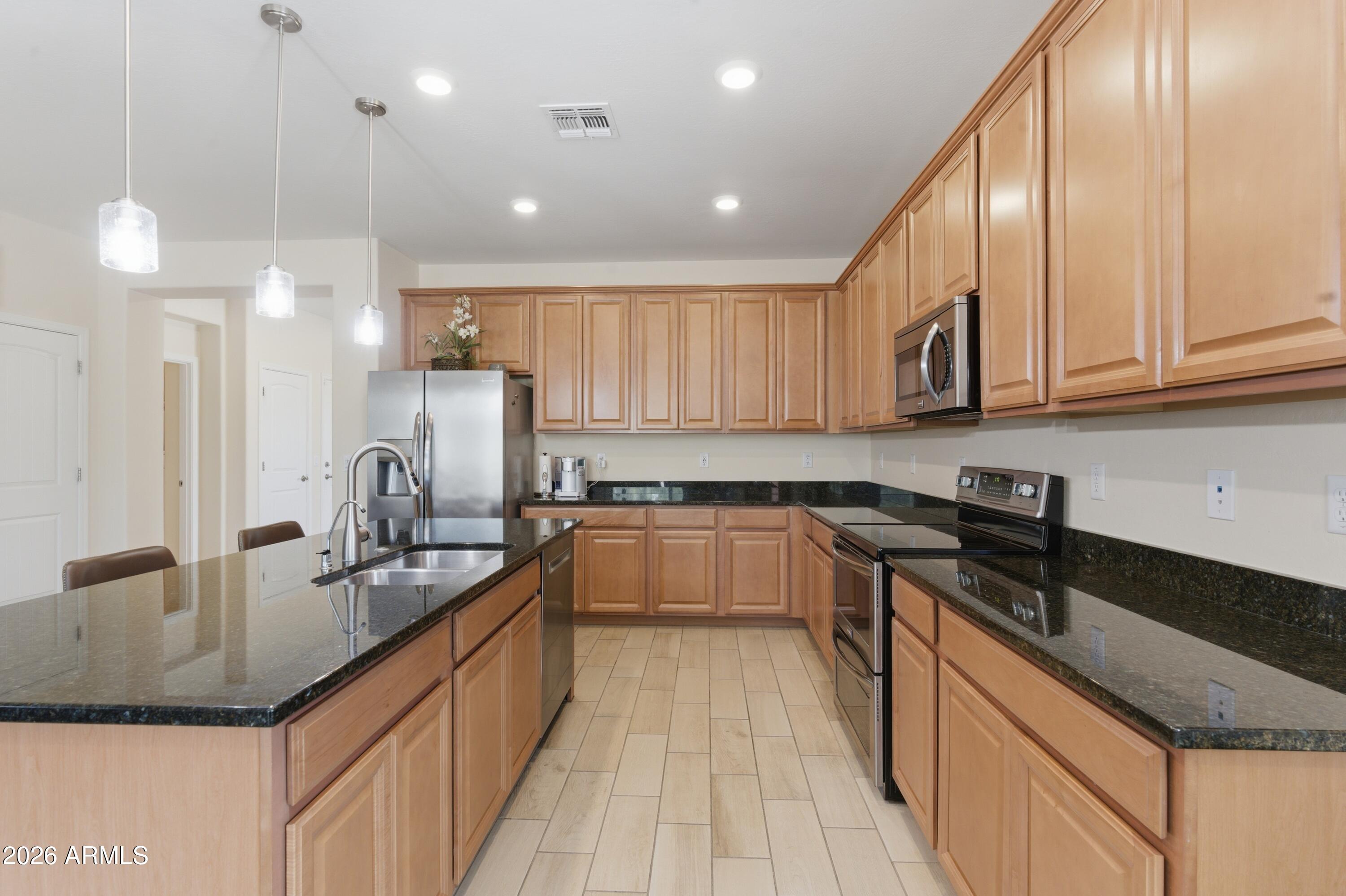 4654 North 204th Lane Buckeye, AZ 85396 - Photo 12 of 41 a kitchen with kitchen island granite countertop a sink a counter top space appliances and cabinets