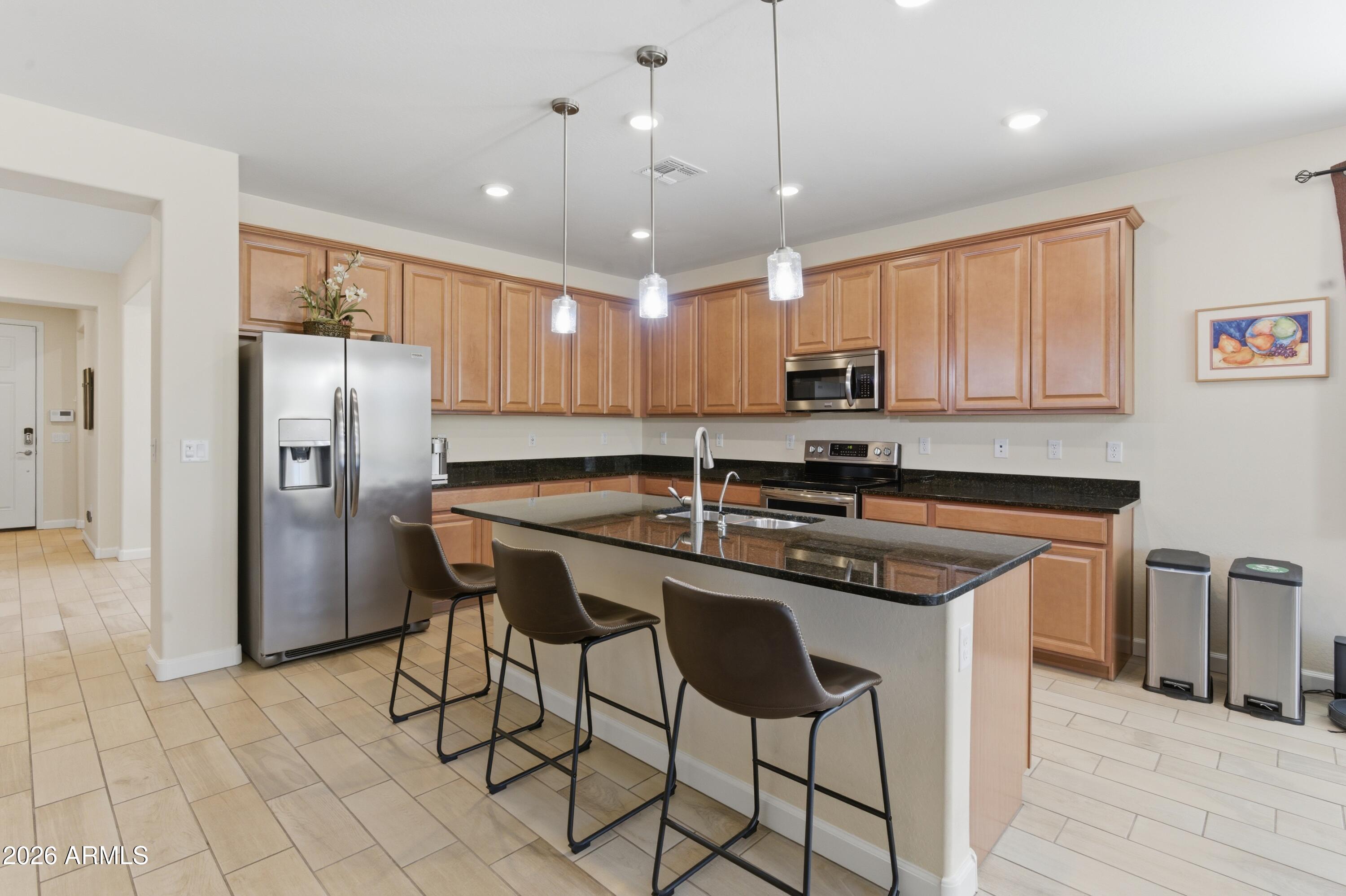 4654 North 204th Lane Buckeye, AZ 85396 - Photo 13 of 41 a kitchen with stainless steel appliances granite countertop a sink a stove a refrigerator and island with wooden floor