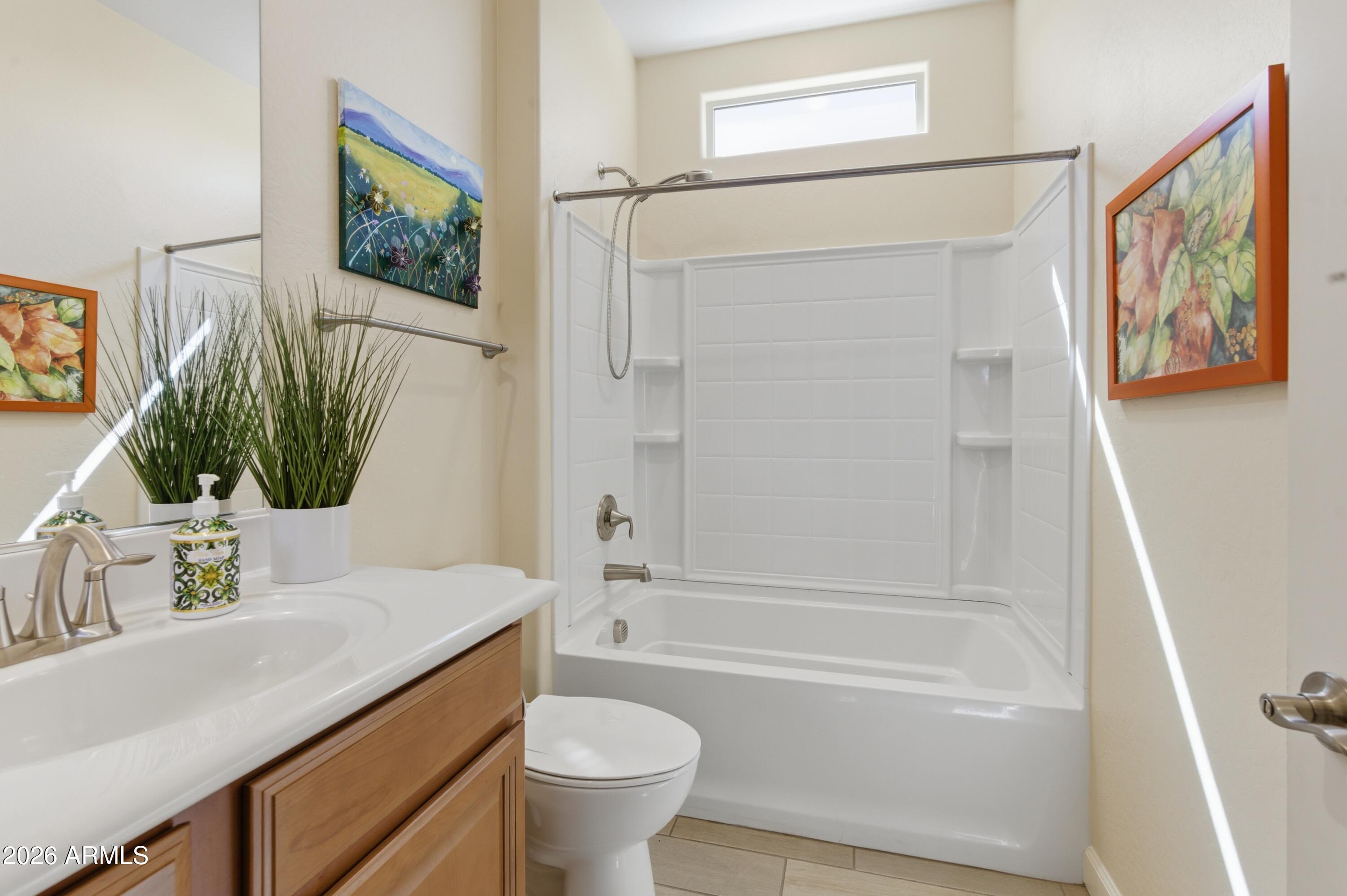 4654 North 204th Lane Buckeye, AZ 85396 - Photo 6 of 41 a bathroom with a sink a mirror a bathtub and a shower