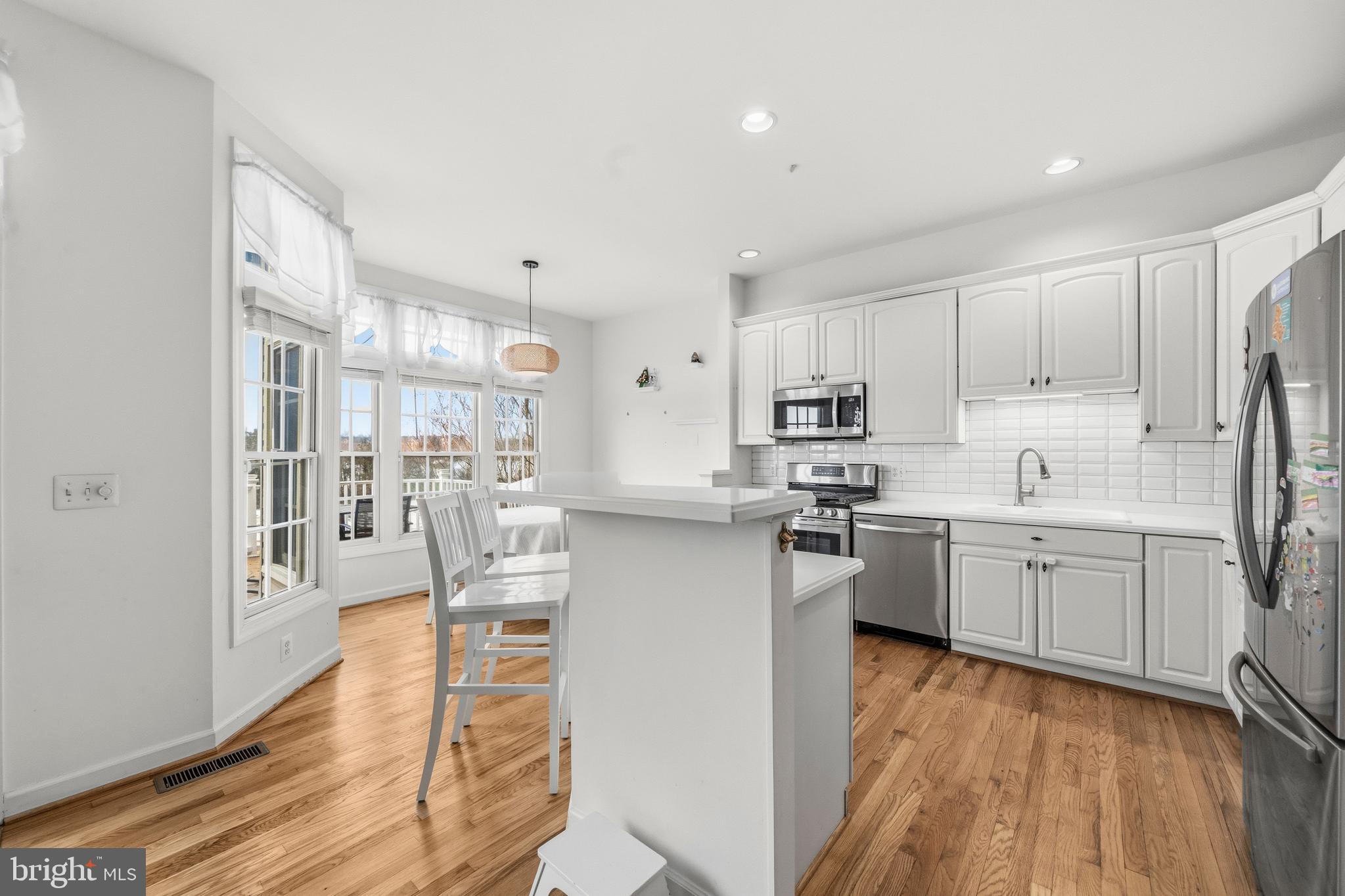 43003 Golf View Drive Chantilly, VA 20152 - Photo 10 of 54 a kitchen with stainless steel appliances granite countertop a refrigerator a stove top oven a sink dishwasher and white cabinets with wooden floor