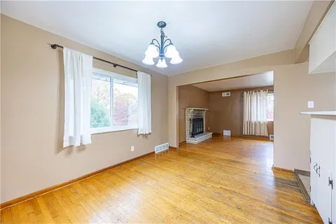 a view of an empty room with window and wooden floor