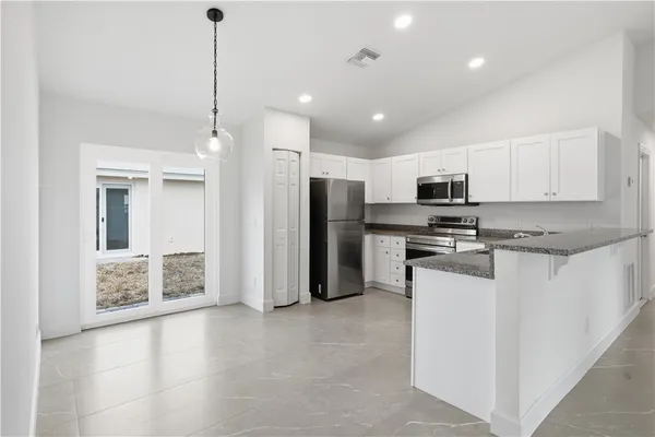 a kitchen with stainless steel appliances granite countertop a refrigerator a stove and a sink