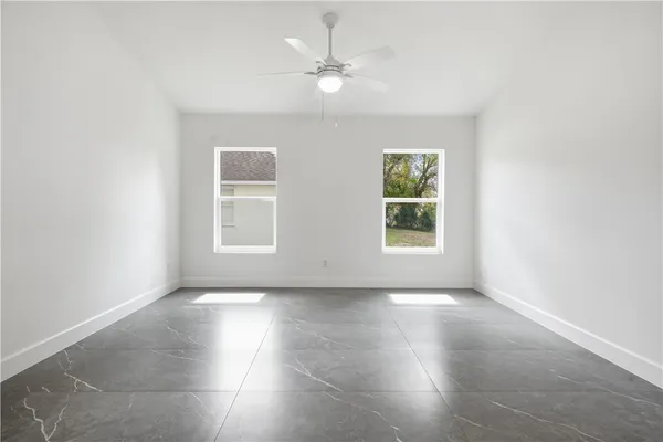 an empty room with windows and ceiling fan