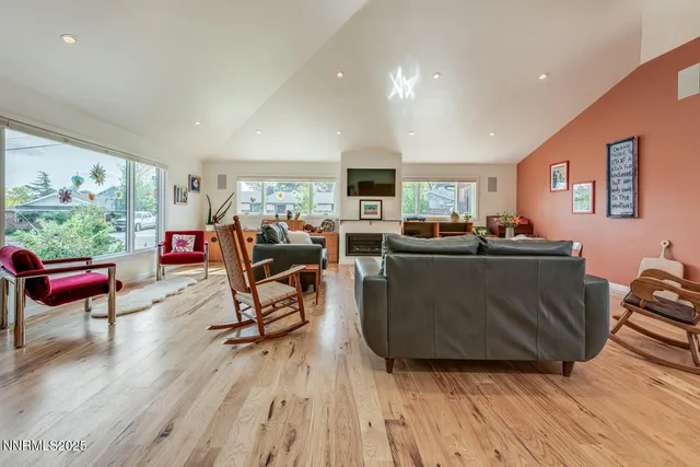 a living room with furniture kitchen view and a wooden floor
