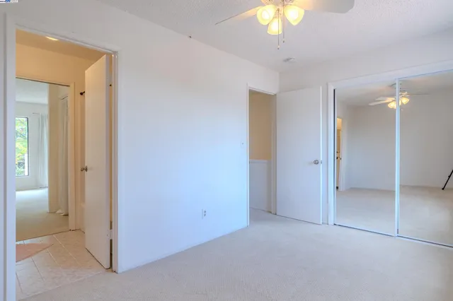 an empty room with a bathroom and a chandelier fan