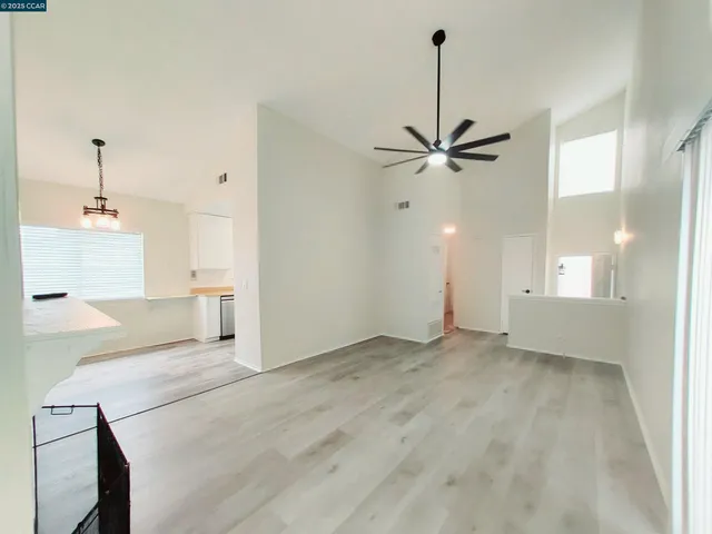 a view of an empty room with a ceiling fan and window