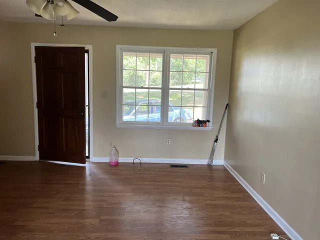 an empty room with wooden floor and windows