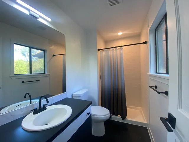 a bathroom with a sink a toilet and shower a mirror