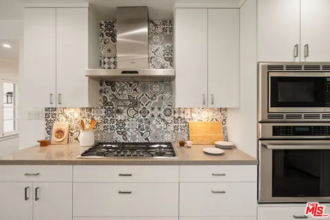 a kitchen with granite countertop a stove and a white cabinets