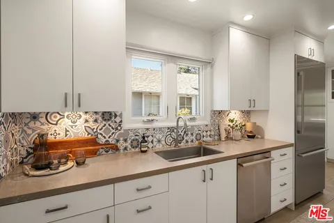 a kitchen with stainless steel appliances granite countertop a sink and white cabinets