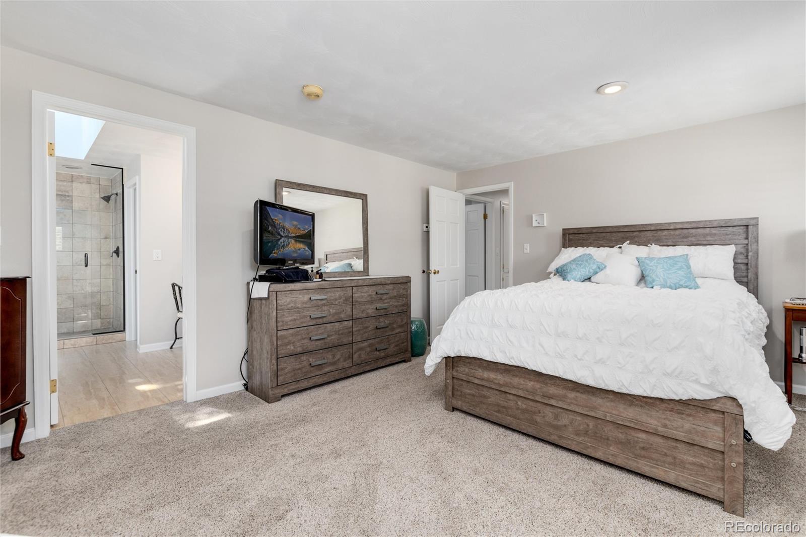 3375 Nelson Street Wheat Ridge, CO 80033 - Photo 18 of 35 a spacious bedroom with a bed and a flat screen tv