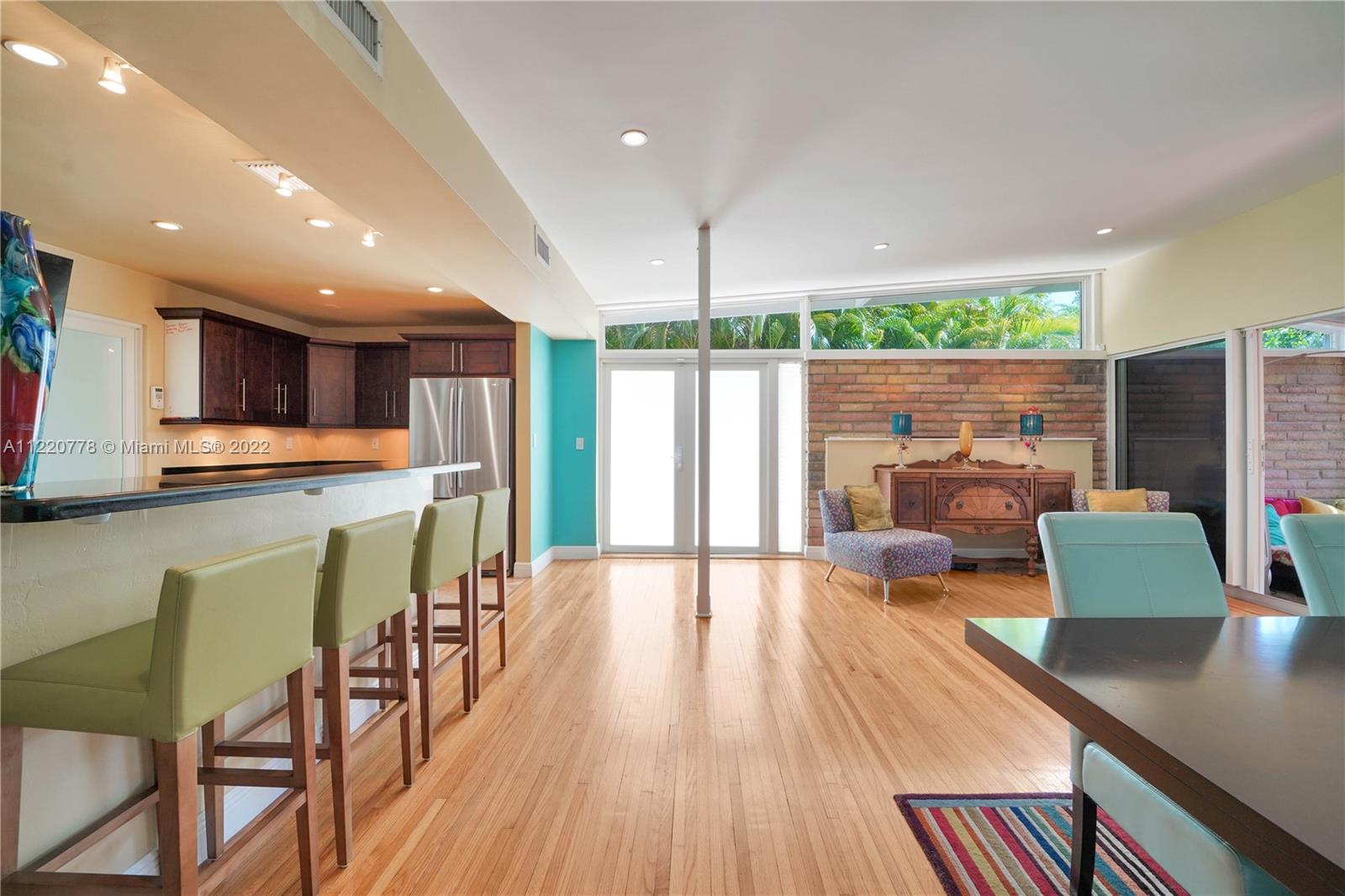 1810 Alamanda Drive North Miami, FL 33181 - Photo 15 of 40 a kitchen with stainless steel appliances granite countertop a refrigerator a stove top oven a dining table and chairs with the wooden floor