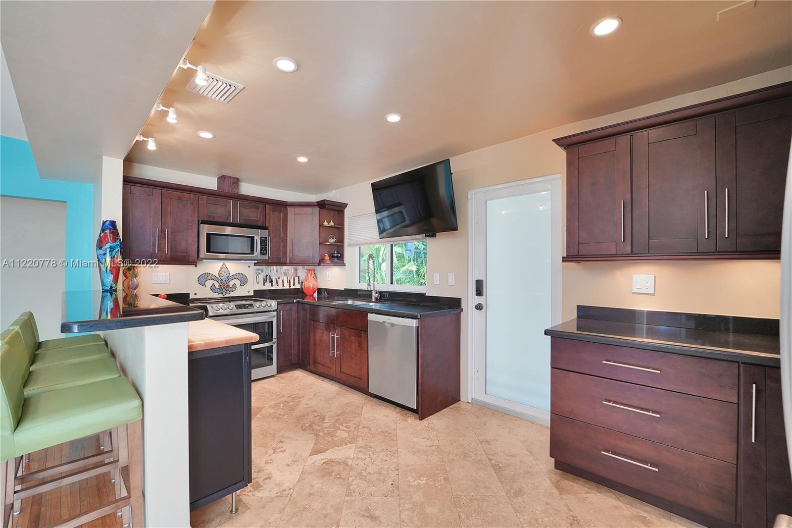 1810 Alamanda Drive North Miami, FL 33181 - Photo 6 of 40 a kitchen with kitchen island granite countertop wooden cabinets and a stove top oven