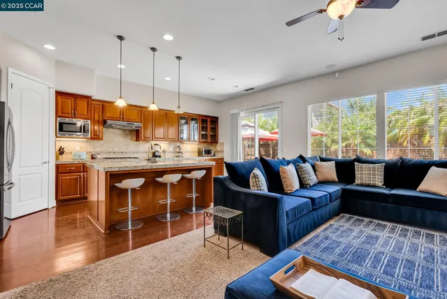 a kitchen with stainless steel appliances granite countertop a stove a sink dishwasher and a refrigerator with wooden floor