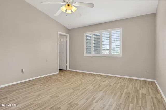 a view of an empty room with chandelier fan and wooden floor