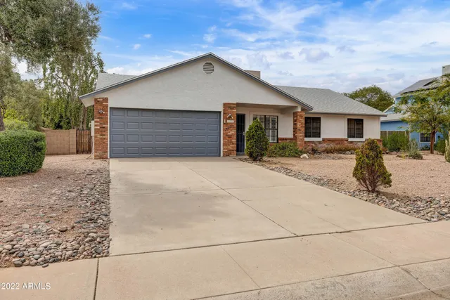 a front view of house with yard and trees in the background