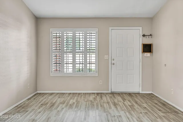 a view of an empty room with wooden floor and a window