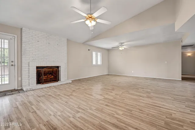 an empty room with wooden floor and chandelier fan