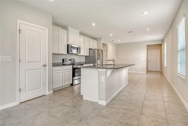 a view of kitchen with kitchen island white cabinets and stainless steel appliances