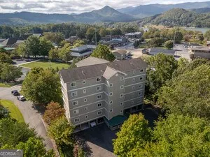 an aerial view of a house with a yard and mountain view in back