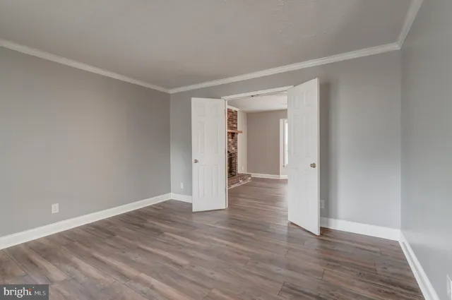 a view of an empty room with window and wooden floor