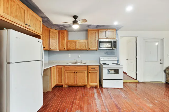 an empty room with wooden floor chandelier and windows