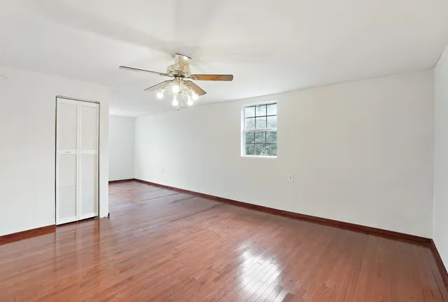 a view of an empty room with chandelier fan and a window