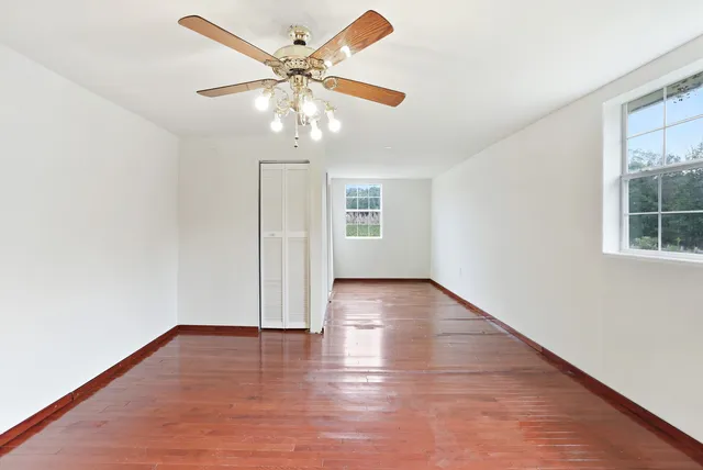 a view of empty room with wooden floor and a window