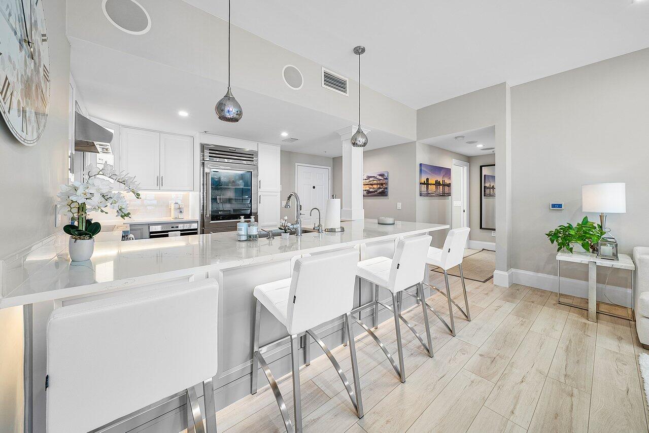255 Evernia Street, Unit 1502 West Palm Beach, FL 33401 - Photo 12 of 40 a kitchen with stainless steel appliances kitchen island granite countertop a table and chairs in it