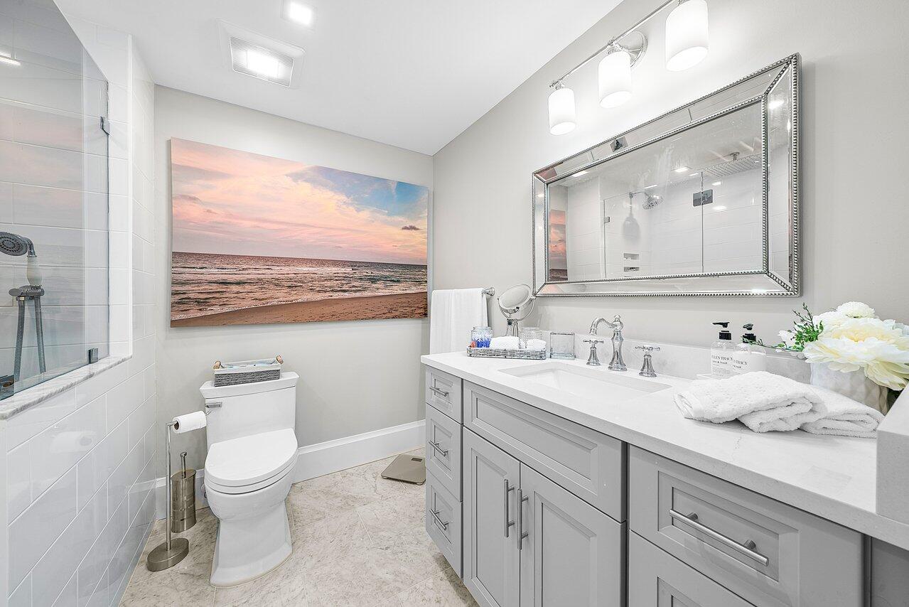 255 Evernia Street, Unit 1502 West Palm Beach, FL 33401 - Photo 19 of 40 a bathroom with a toilet a sink and a large mirror