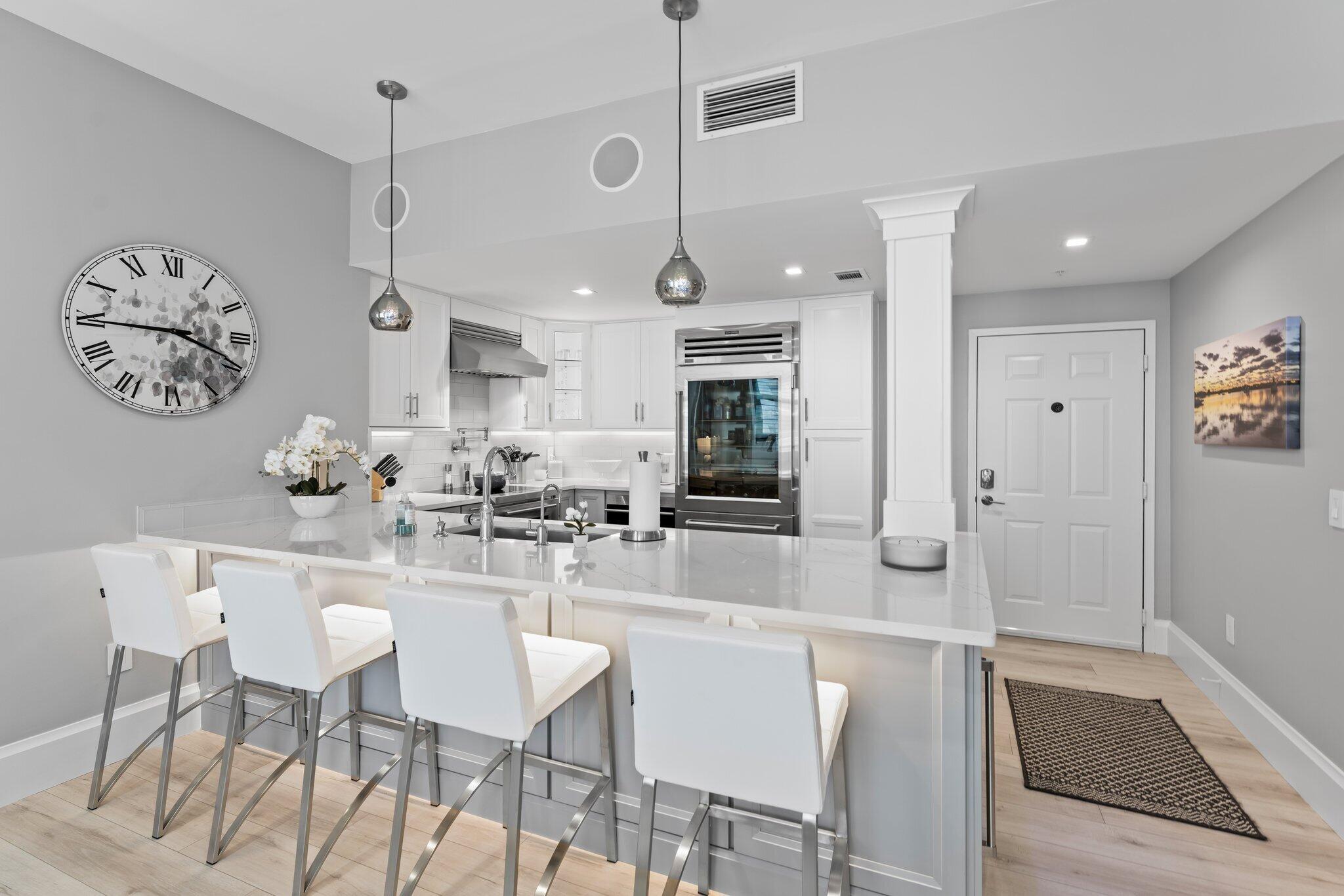 255 Evernia Street, Unit 1502 West Palm Beach, FL 33401 - Photo 3 of 40 a kitchen with stainless steel appliances kitchen island granite countertop a dining table chairs and white cabinets