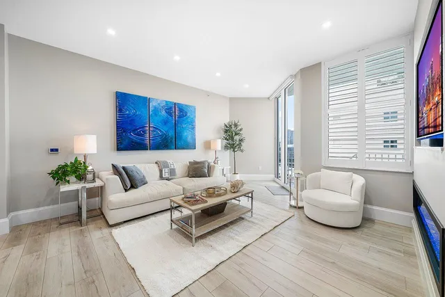 a living room with furniture kitchen view and a wooden floor