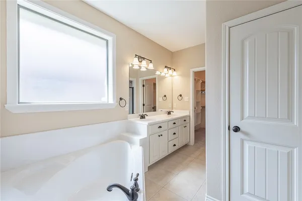a bathroom with a tub sink and mirror