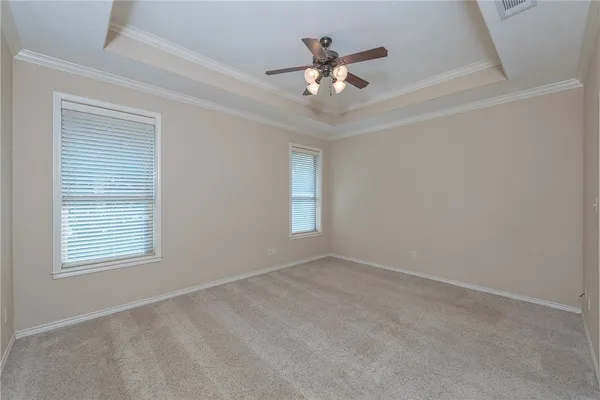 an empty room with chandelier fan and windows