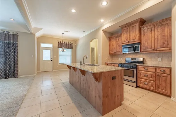 a kitchen with stainless steel appliances granite countertop a stove top oven a sink dishwasher and a refrigerator with wooden cabinets
