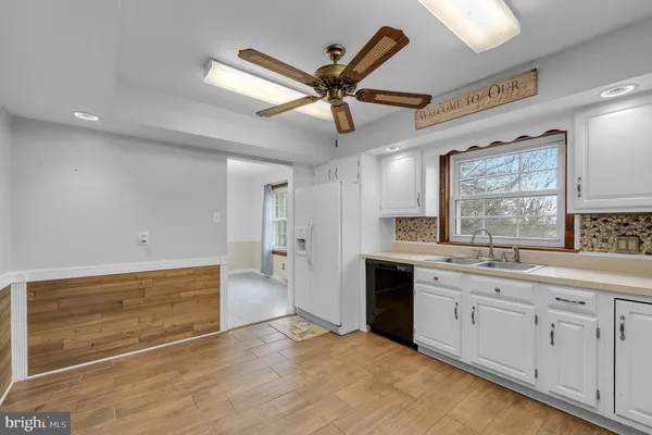 a living room with stainless steel appliances kitchen island granite countertop a refrigerator a sink dishwasher a dining table and chairs with wooden floor
