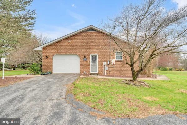 a brick house next to a yard with large trees