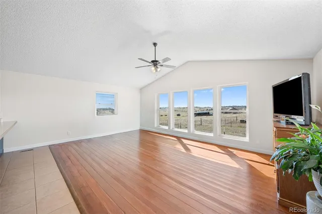 a view of a livingroom with wooden floor and a ceiling fan