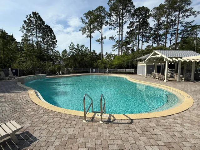 a view of a swimming pool with lawn chairs under an umbrella