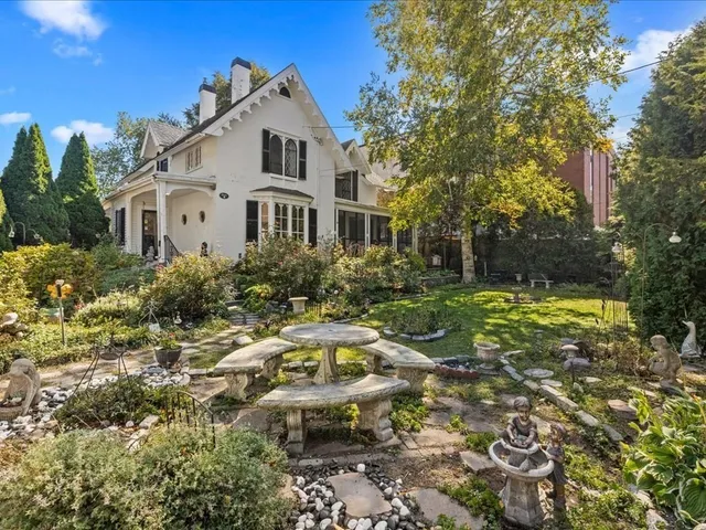 a view of a white house with a big yard and large trees