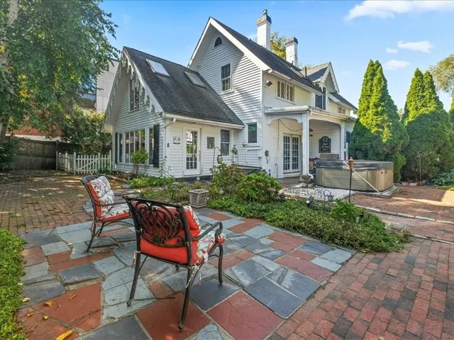 a view of a brick house with table and chairs in patio