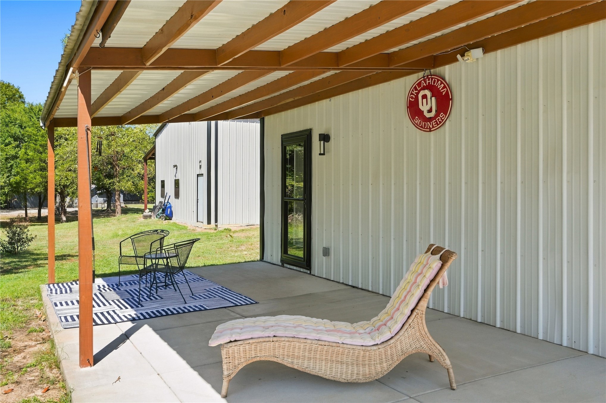 Covered concrete patio with wood-finish support beams and a corrugated metal roof