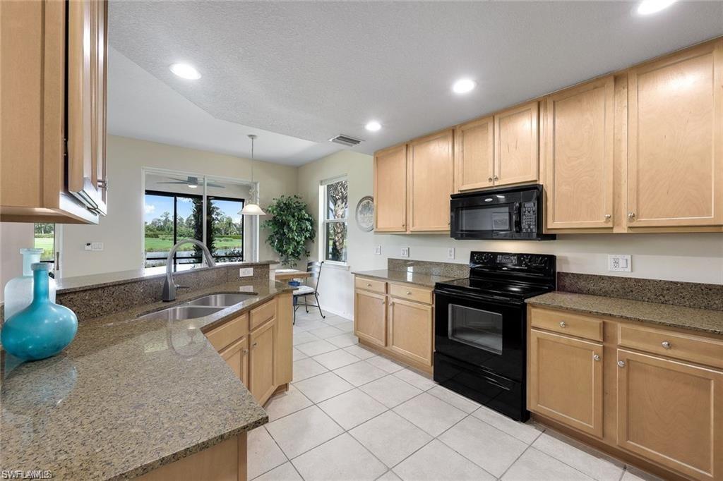 9525 Ironstone Terrace, Unit 102 Naples, FL 34120 - Photo 11 of 35 a kitchen with stainless steel appliances granite countertop a stove a sink and a microwave