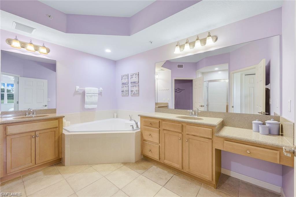 9525 Ironstone Terrace, Unit 102 Naples, FL 34120 - Photo 14 of 35 a spacious bathroom with a bathtub sink and mirror
