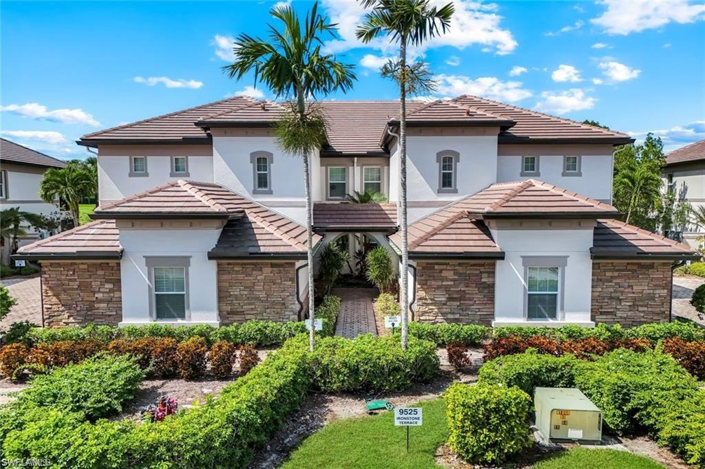 9525 Ironstone Terrace, Unit 102 Naples, FL 34120 - Photo 22 of 35 a front view of a house with a garden and palm trees