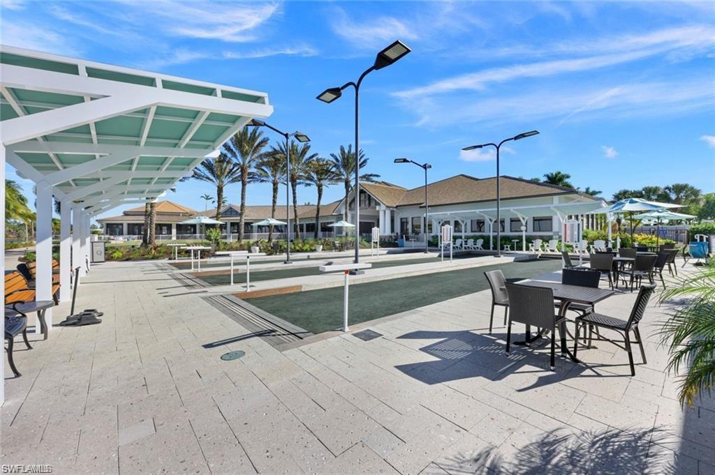 9525 Ironstone Terrace, Unit 102 Naples, FL 34120 - Photo 31 of 35 a view of a patio with dining table and chairs with a small yard
