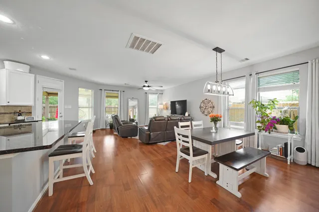 a living room with furniture kitchen view and a wooden floor