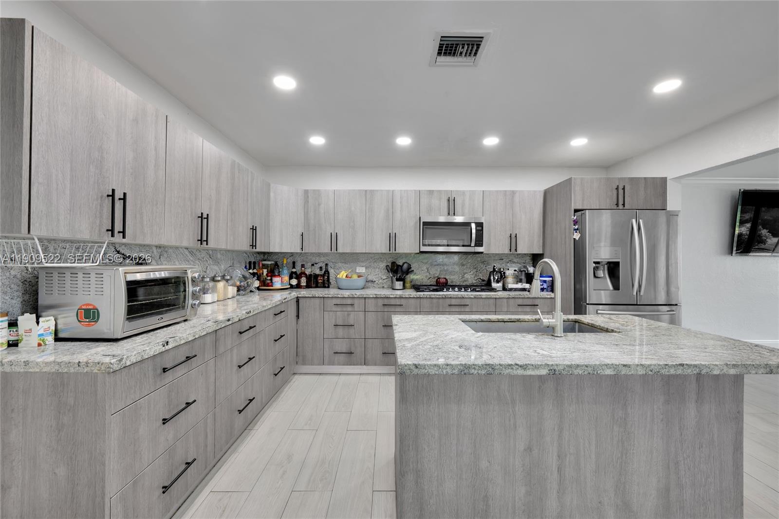 6221 Southwest 26th Street Miramar, FL 33023 - Photo 4 of 24 a kitchen with kitchen island granite countertop stainless steel appliances and white cabinets