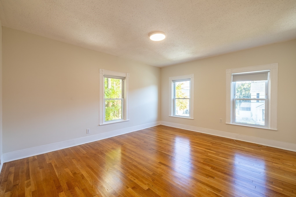 365 Whiting Avenue, Unit 2 Dedham, MA 02026 - Photo 12 of 15 a view of an empty room with wooden floor and a window